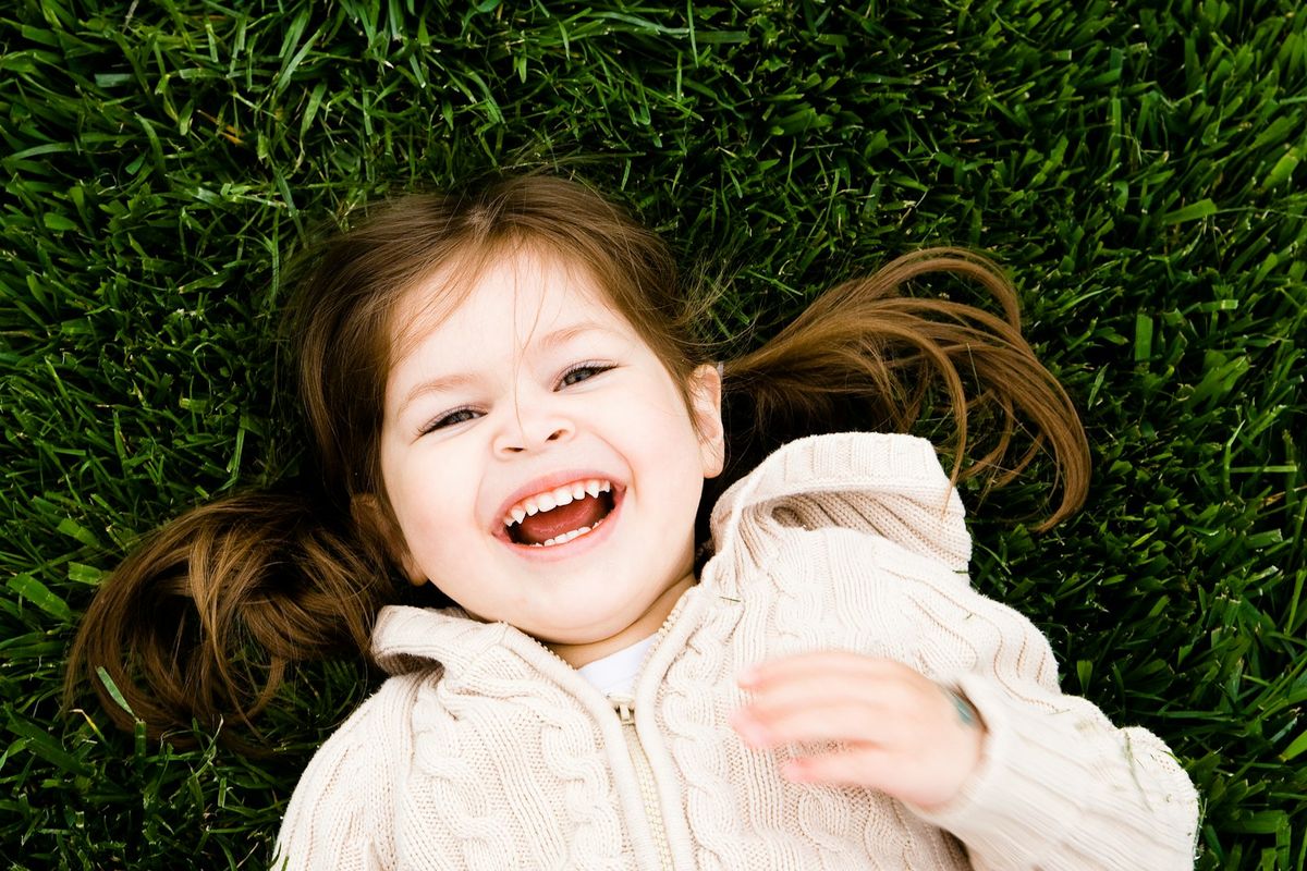 Leende barn med friskt smil ute i gresset