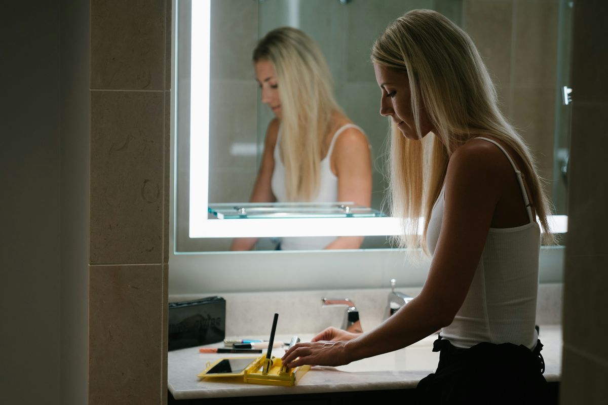 Kvinne som ser seg i speilet på badet